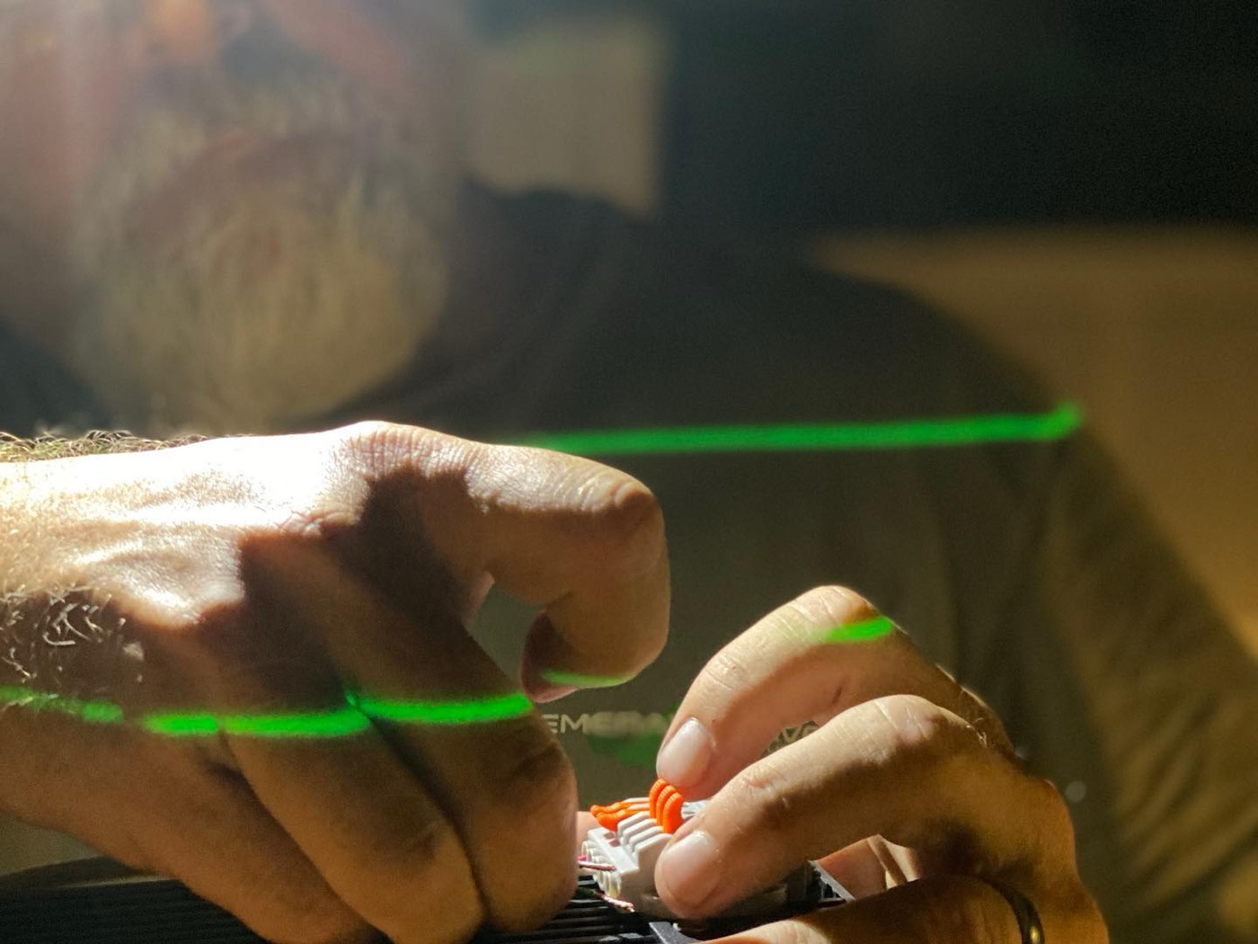 Technician's hands working on equipment under a green laser line