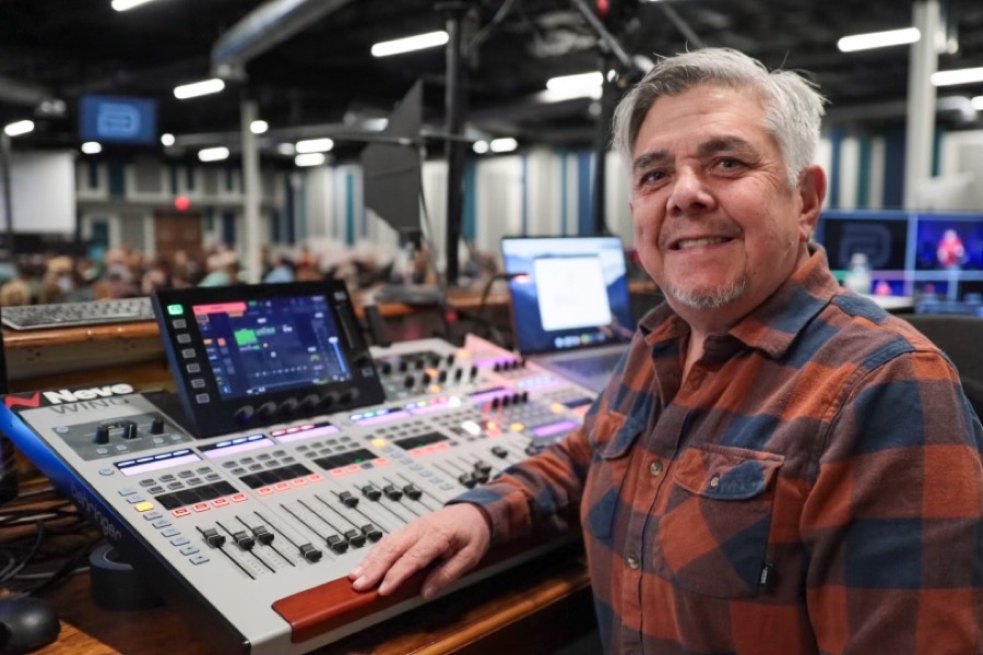 Front-of-house engineer smiling behind a digital mixing console during a church service