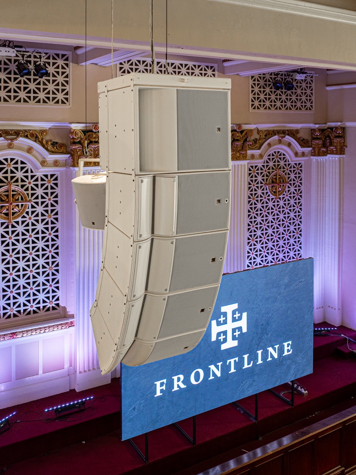White line array flown beside ornate plasterwork inside Frontline Church